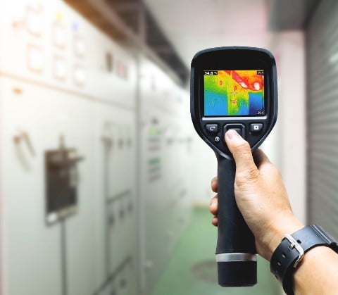 Inspector using an infrared thermal imaging camera during a property inspection